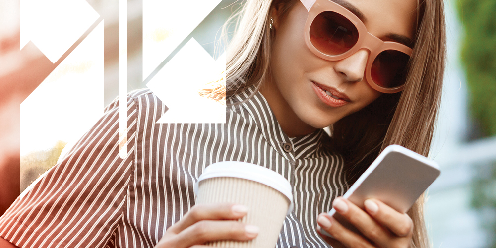 Blonde woman reading her phone while holding coffee